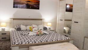 Ein Schlafzimmer mit einem großen Bett, zwei Nachttischen mit Lampen, einem Spiegel und einem Bild an der Wand.