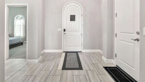 A hallway with a white door, a small window with a sheer curtain, and a light-colored floor. - EAZY AZ Modern 2 bedroom townhouse on the 8th fairway of Estrella Mountain Ranch (Goodyear)