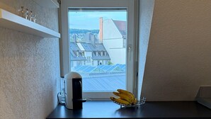 A small kitchenette with a window, a coffee maker, and a banana holder. - Maison Züri Charming Retreat in Wiedikon, Just 16 Minutes from Lake Zurich (Zürich)