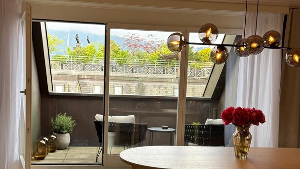 A spacious room with a large sliding glass door leading to an outdoor area, a wooden dining table, and a cozy seating area. - Maison Züri Charming Retreat in Wiedikon, Just 16 Minutes from Lake Zurich (Zürich)