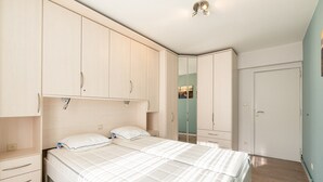 A bedroom with a bed, a wardrobe, a mirror, and a door. - Apartment in Blankenberge with Sea Views (Blankenberge)