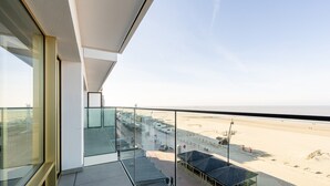 A modern hotel balcony with a view of the beach and a parking area. - Apartment in Blankenberge with Sea Views (Blankenberge)