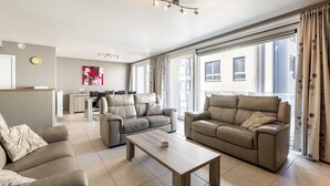 Ein modernes Wohnzimmer mit zwei Sofas, einem Couchtisch und einem Essbereich im Hintergrund.