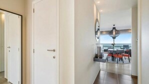 A modern interior with a dining area featuring a table and chairs, a large mirror, and a view of the sea. - Apartment in Blankenberge with Ocean Views (Blankenberge)
