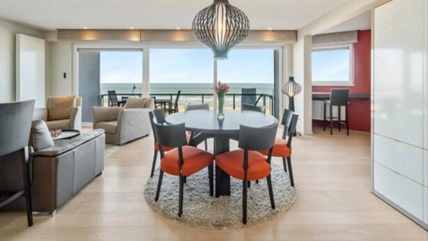 A spacious living area with a round table and chairs, a sofa, and a view of the ocean. - Apartment in Blankenberge with Ocean Views (Blankenberge)