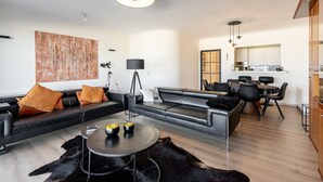 A modern living room with a sofa, coffee table, and dining area. - Apartment in Zeedijk with Stunning Sea Views (Blankenberge)