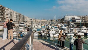 A marina with boats docked, a pedestrian walkway, and residential buildings in the background. - Apartment in Blankenberge with Sea Views (Blankenberge)