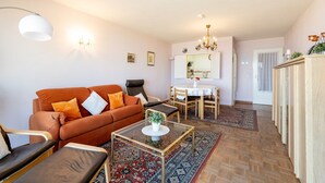 Ein Wohnzimmer mit Sofa, Sesseln, Couchtisch und Essbereich mit Tisch und Stühlen.