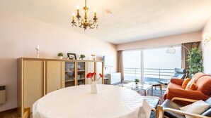 Ein Hotelzimmer mit einem runden Esstisch, einer Couch, einer Minibar und einem Balkon mit Blick.