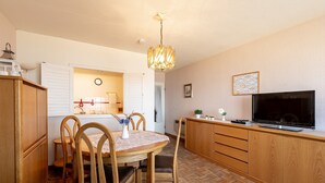 A compact kitchen with a dining area, wooden cabinets, a television, and a chandelier. - Apartment in Blankenberge near Belgian Pier (Blankenberge)