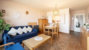 A cozy living room with a blue sofa, wooden dining table, and chairs. - Apartment in Blankenberge near Belgian Pier (Blankenberge)
