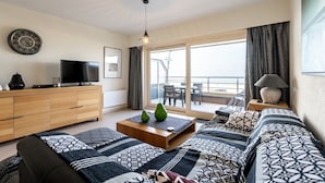 Ein modernes Wohnzimmer mit Sofa, Couchtisch, Fernseher und einem Balkon mit Blick.