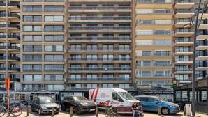 Ein mehrgeschossiges Wohngebäude mit Balkonen und einem parkenden Transporter davor.