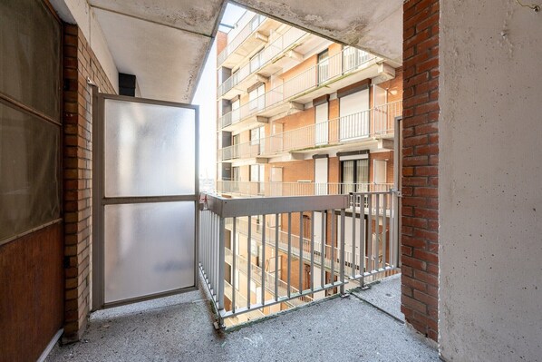 Un corridoio stretto con un cancello in metallo che conduce a un edificio a più piani con balconi.