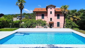 Eine rosa Villa mit Schwimmbecken davor.