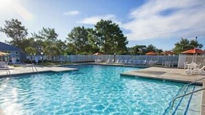 A clear swimming pool with a metal ladder, surrounded by lounge chairs and a fence. - Sanibel Summer Hideaway | Waterfront Oasis (Rehoboth Beach)