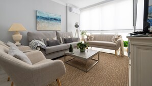 Una sala de estar con un sofá, sillones, una mesa de centro y un televisor.