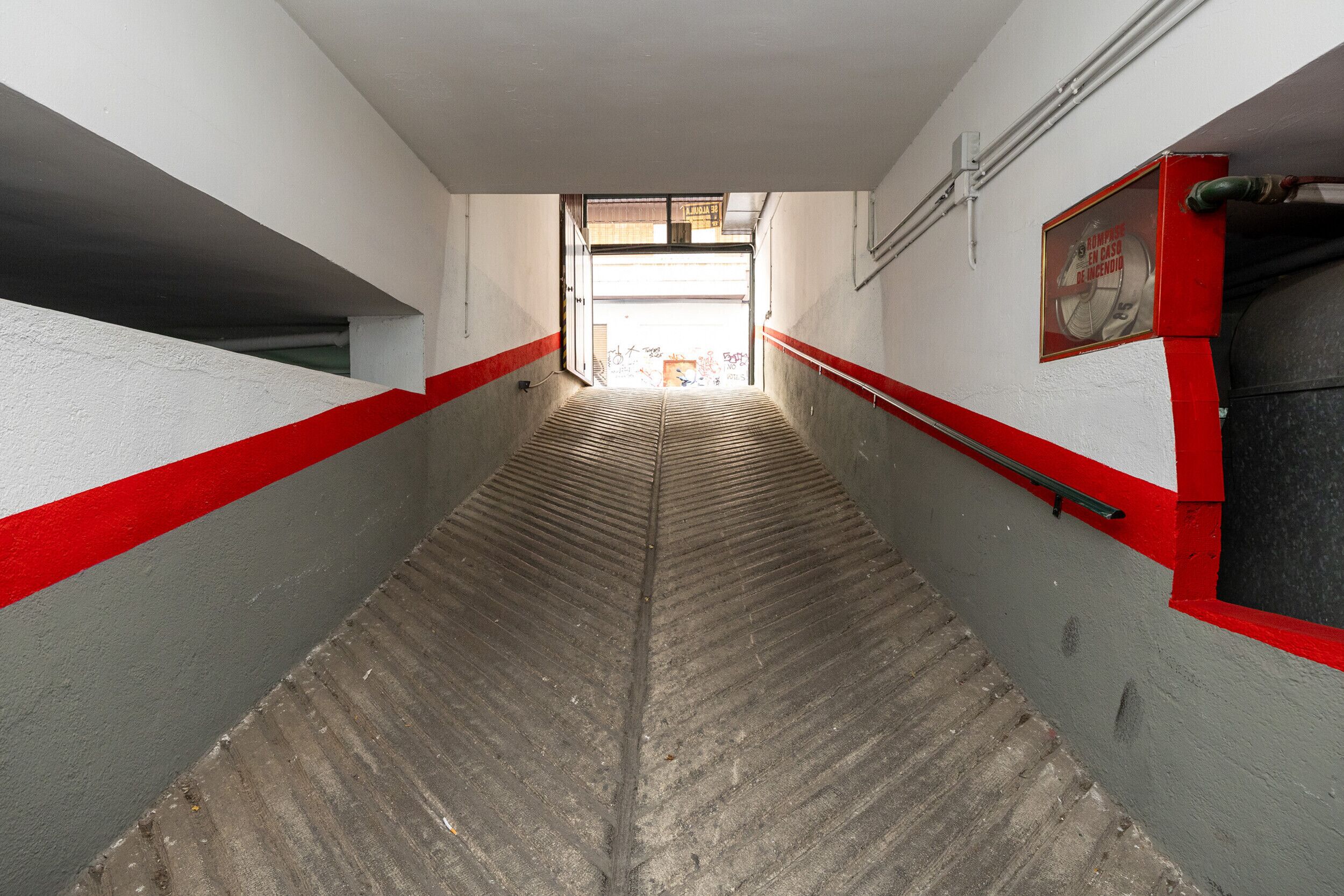 A stairway with red and grey walls, leading to an open doorway.