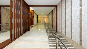 Pasillo de hotel con piso de mármol, un separador de madera y barandilla de metal.