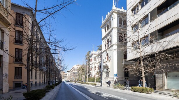 Uma rua com edifícios de vários andares, alguns com varandas e detalhes arquitetônicos.