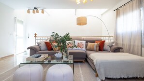Una sala moderna con un conjunto de sofá, una mesa de centro de vidrio y un ventanal con cortinas.