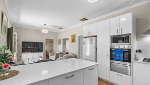 Une cuisine moderne avec des meubles blancs, un îlot central et des appareils en acier inoxydable.