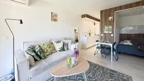 A modern living room with a sofa, coffee table, and a dining area with chairs.