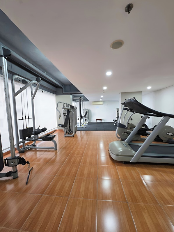 Un gimnasio con equipo de ejercicio, una cinta de correr y un banco.