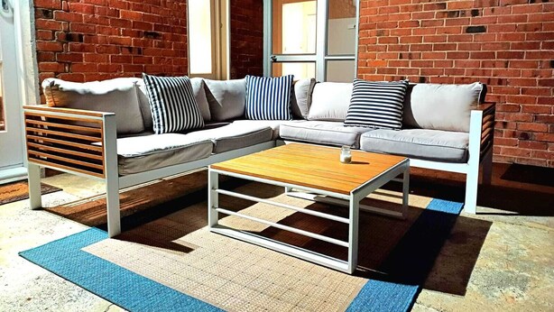 Una sala de estar moderna con un sofá modular, una mesa de centro de madera y una alfombra azul y beige.