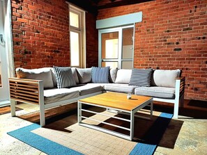 En moderne stue med en hjørnesofa, et træbord og en blå og beige måtte.