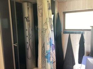 Un baño con cortina de ducha con diseño de instrumento musical, un perchero con una toalla y una ventana con vistas al exterior.