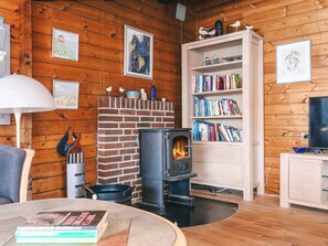 A cozy living room with a brick fireplace, a bookshelf, and a television. - 6 Person Holiday Home in Henne (Henne)