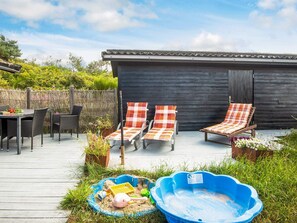 An outdoor patio with two lounge chairs, a table, and a wooden deck. - 6 Person Holiday Home in Henne (Henne)