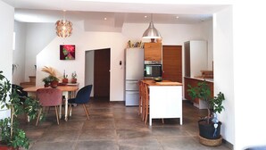 A modern kitchen with a built-in oven and a white refrigerator. There is a dining area with a table and chairs, and a potted plant on the floor. - Country house in Provence (Istres)