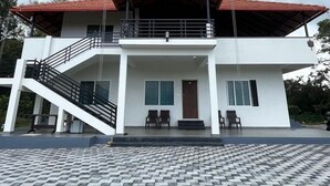 Un bâtiment à deux étages, doté d’un toit rouge, d’un escalier menant à l’étage supérieur et d’une zone d’entrée pavée.
