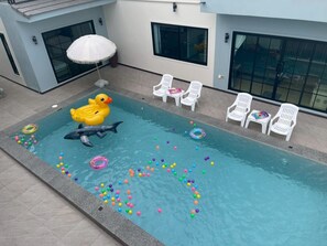 A swimming pool with inflatable toys, colorful balls, and white chairs. - Level FIVE pool villa Pattaya (Bang Lamung)