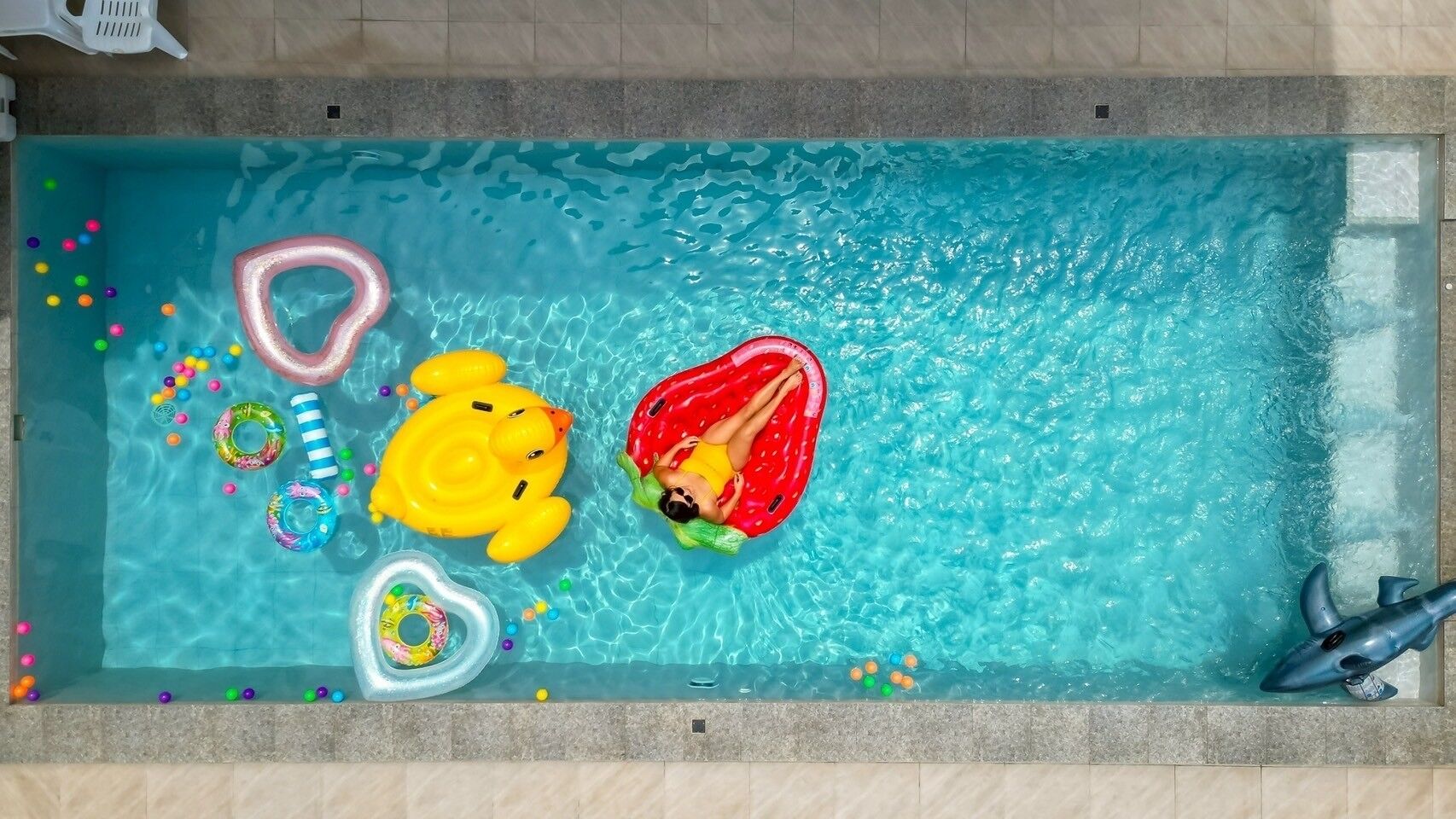 Une piscine avec différents jeux gonflables et un flotteur en forme de requin.
