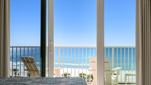 Ein Balkon mit freiem Blick auf das Meer, weißen Stühlen und einem Bett mit gemustertem Überwurf.