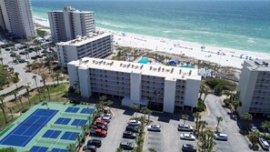Ein Hotel mit mehreren Etagen, einem Parkplatz und Blick auf den Strand.