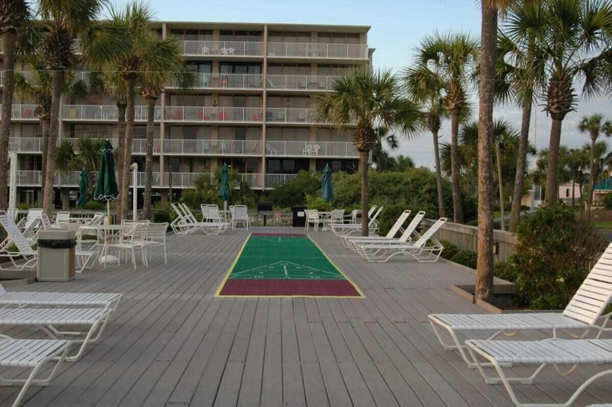 A pool area with lounge chairs and a green sports court.