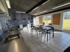 Cozinha moderna com área de jantar, janelas amplas e vista para o exterior.