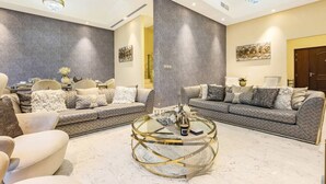 A modern living room with two sofas, a glass coffee table, and a chandelier. - Stylish 4BR Family Villa – Easy Access to Dubai Marina & Expo City (Dubai)