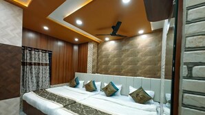 A hotel room with a large bed, wooden paneling, a stone accent wall, and a ceiling fan. - kailash pati guest house (Varanasi)