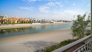A river with a sandy beach and buildings in the background.
