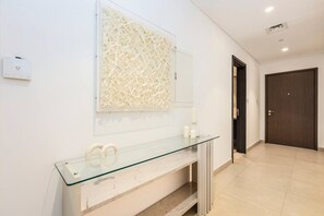 Un baño moderno con un tocador de vidrio, un adorno en la pared y una puerta de madera oscura.