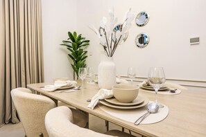 A dining area with a table set for four, including plates, bowls, cutlery, and wine glasses. - FIRST CLASS | 1BR | Stylish Gem | Near Dubai Mall (Downtown)