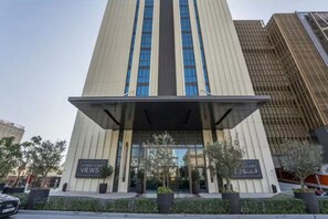 Un edificio moderno con una entrada destacada, grandes ventanales y un área cubierta con señalización.
