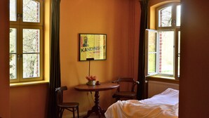 A room with two windows, a table with a vase, a chair, and a bed. - Double room in the Gasthaus am Finowkanal (former school from 1875). (Wandlitz)