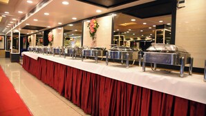 Montaje tipo bufé con varias estaciones de comida, alfombra roja y arreglos florales decorativos.