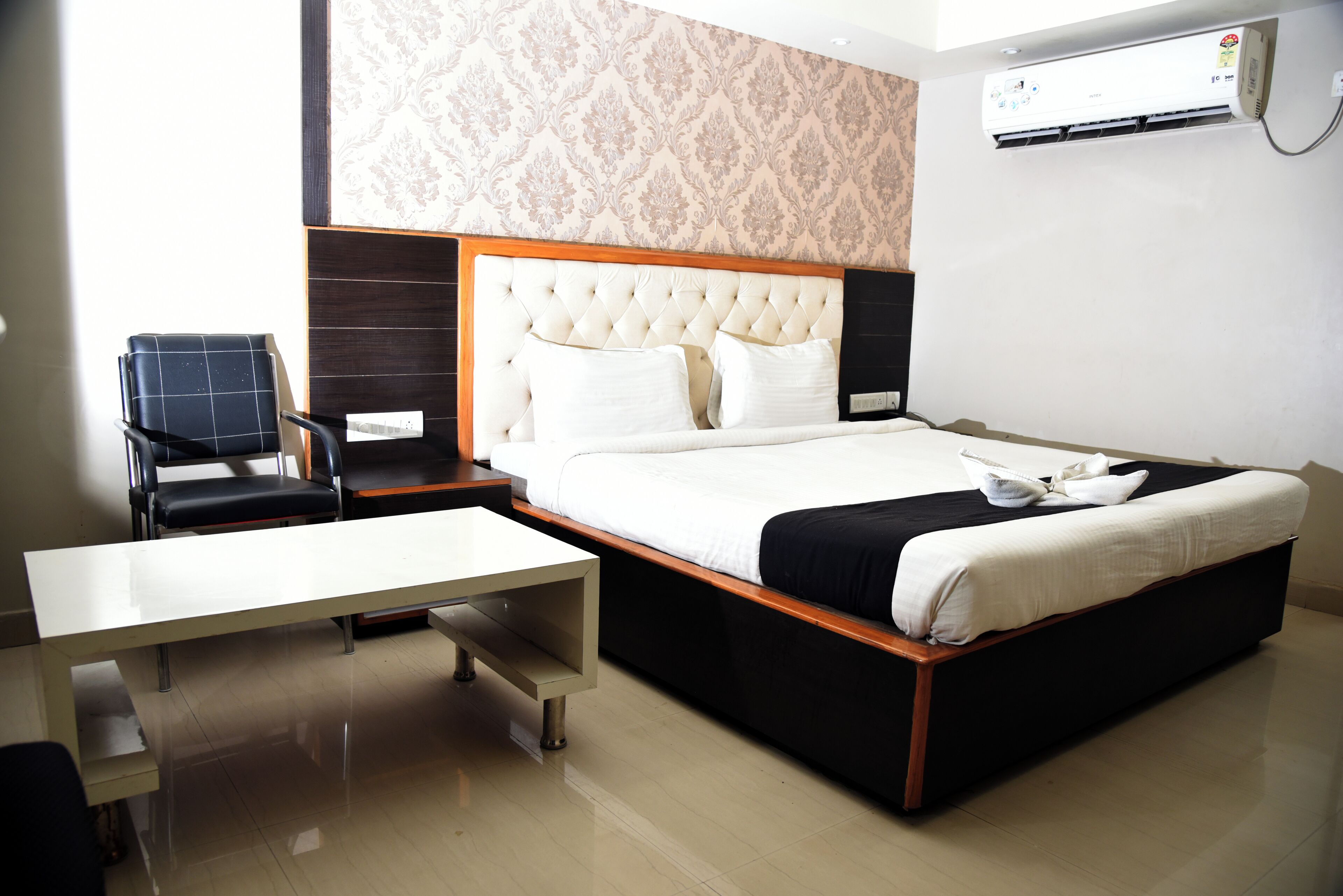 Une chambre d’hôtel équipée d’un lit, d’une chaise, d’un bureau et d’un appareil de climatisation.